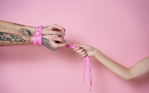 two persons showing only arms and hands tied with bondage rope