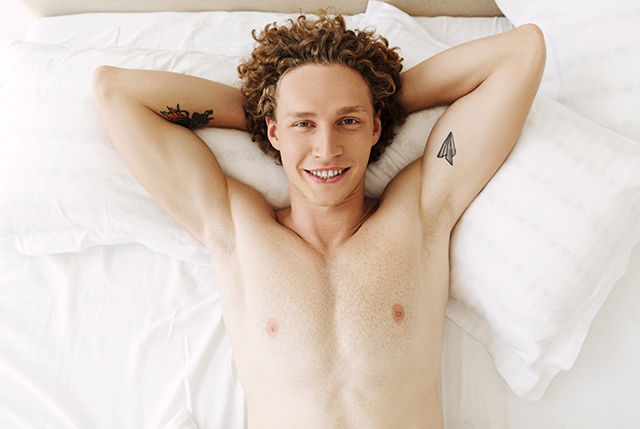shirtless guy in bed ready to play with life-size masturbators